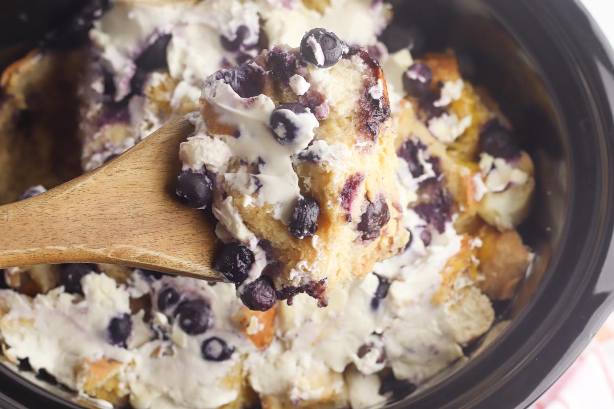 a spoon showing the delicious French toast breakfast casserole with blueberries and cream cheese. The perfect holiday breakfast for families.