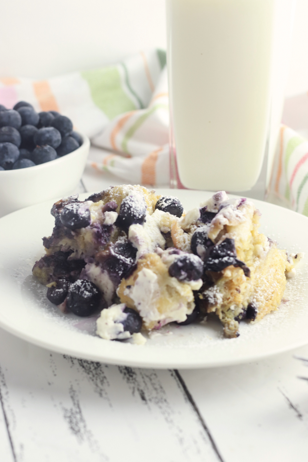 sideview of a delicious breakfast casserole with blueberries and a creamy cheese mixture.