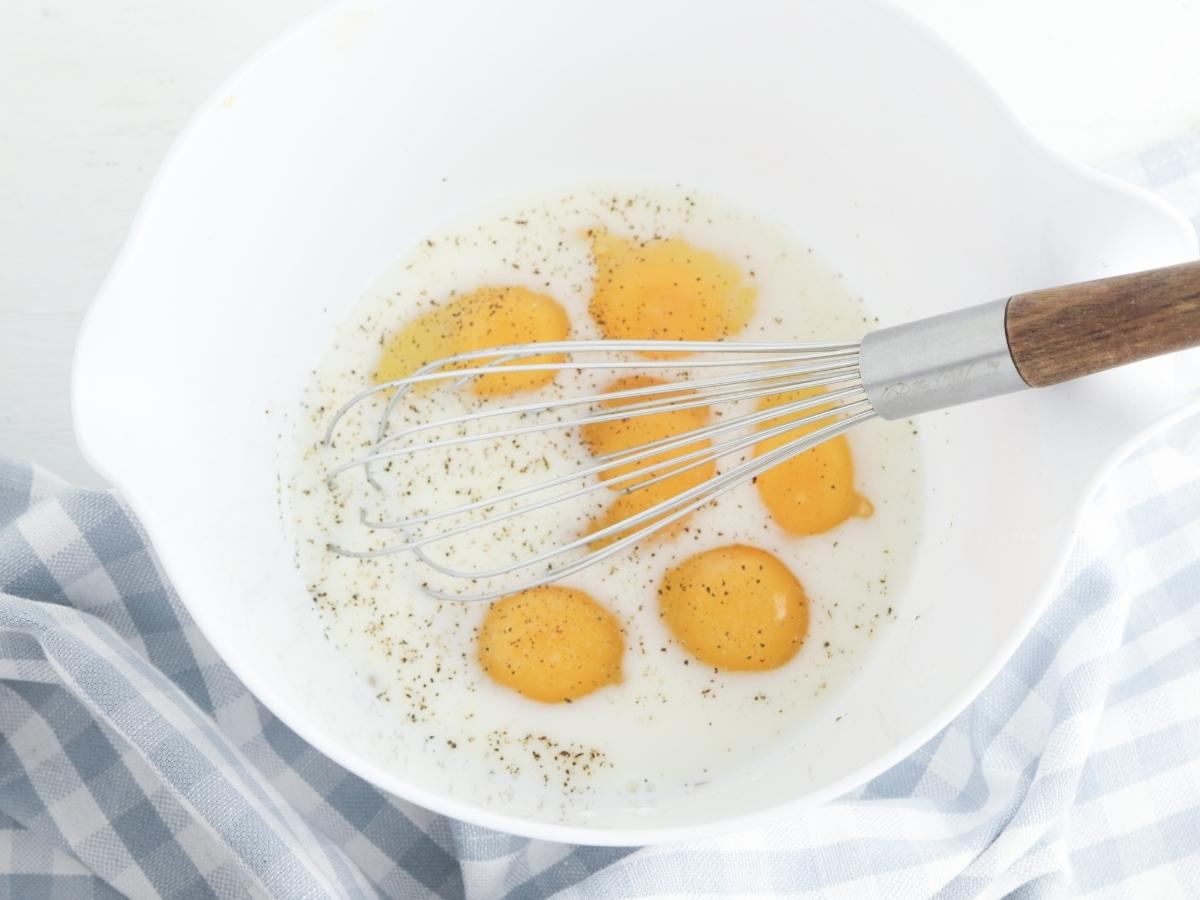 whisking the egg, milk and salt and pepper together to make breakfast cups