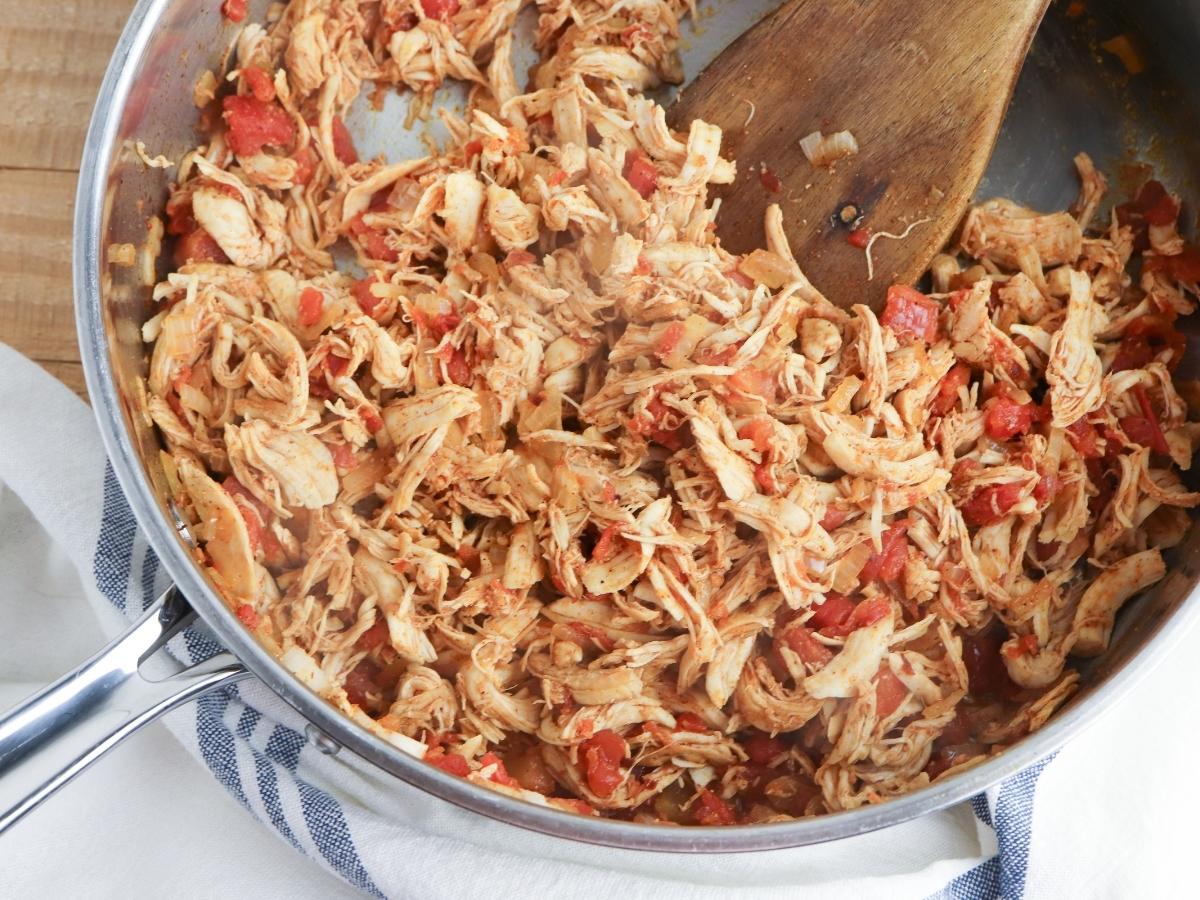 Shredded turkey mixed with onions and red peppers as well as homemade taco seasoning in a skillet pan.