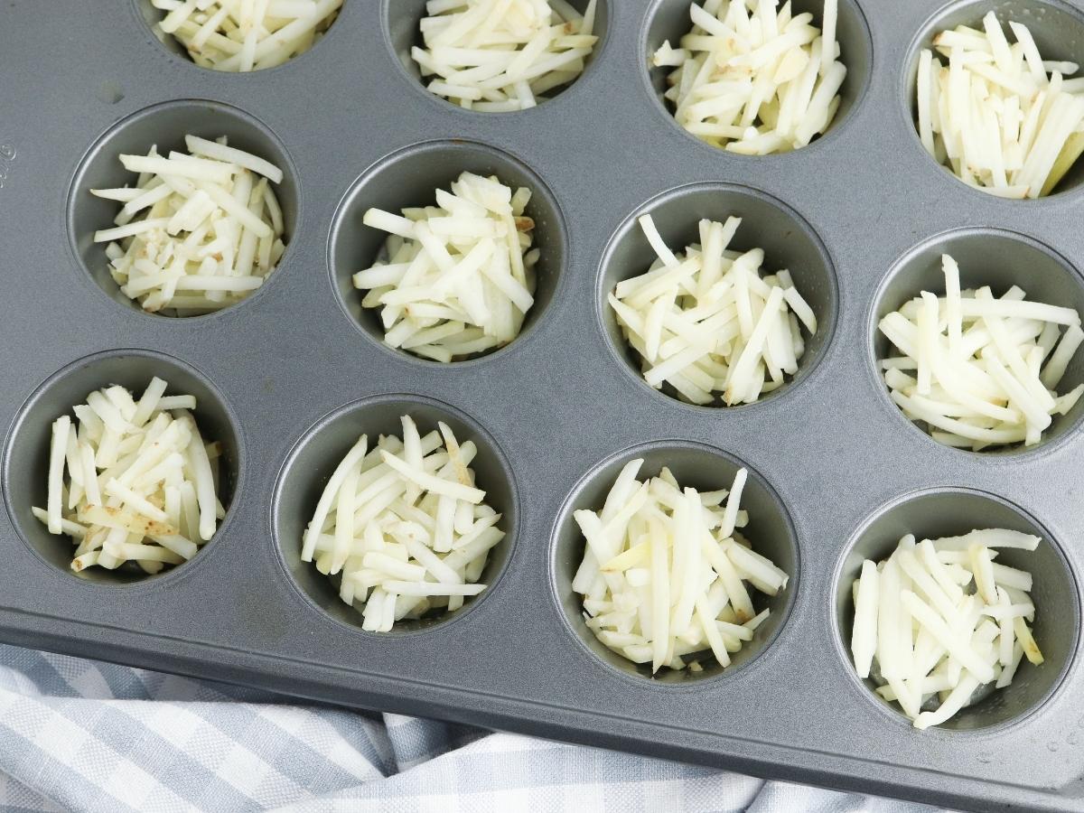 muffin pan cups half filled with shredded hash browns