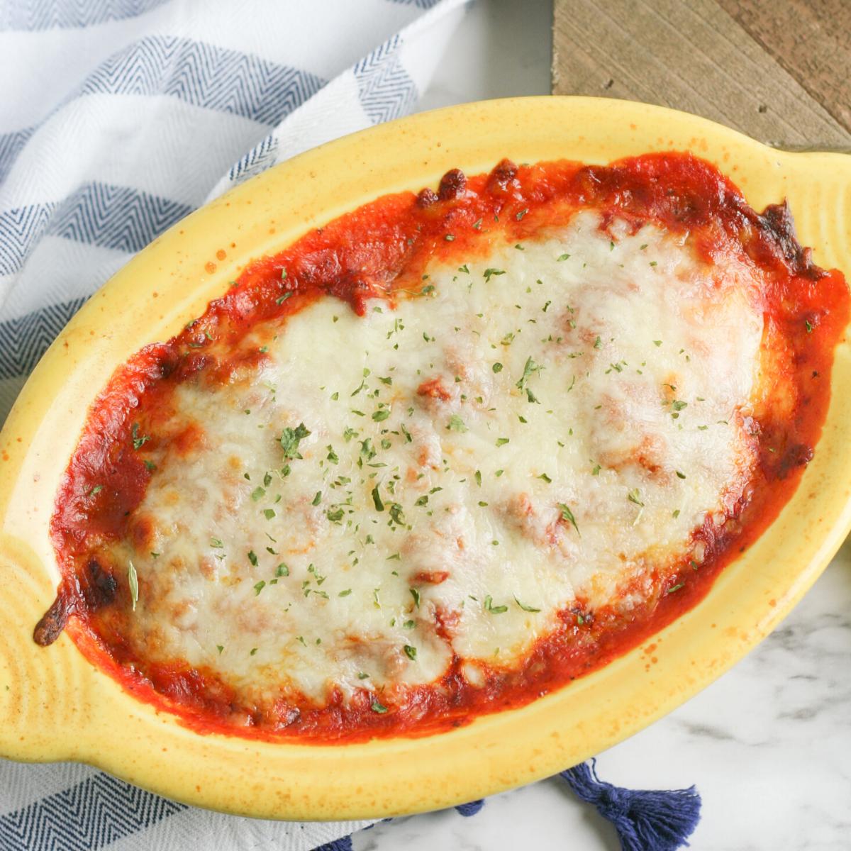 lasagna in a yellow baking dish with lots of melted cheese on top