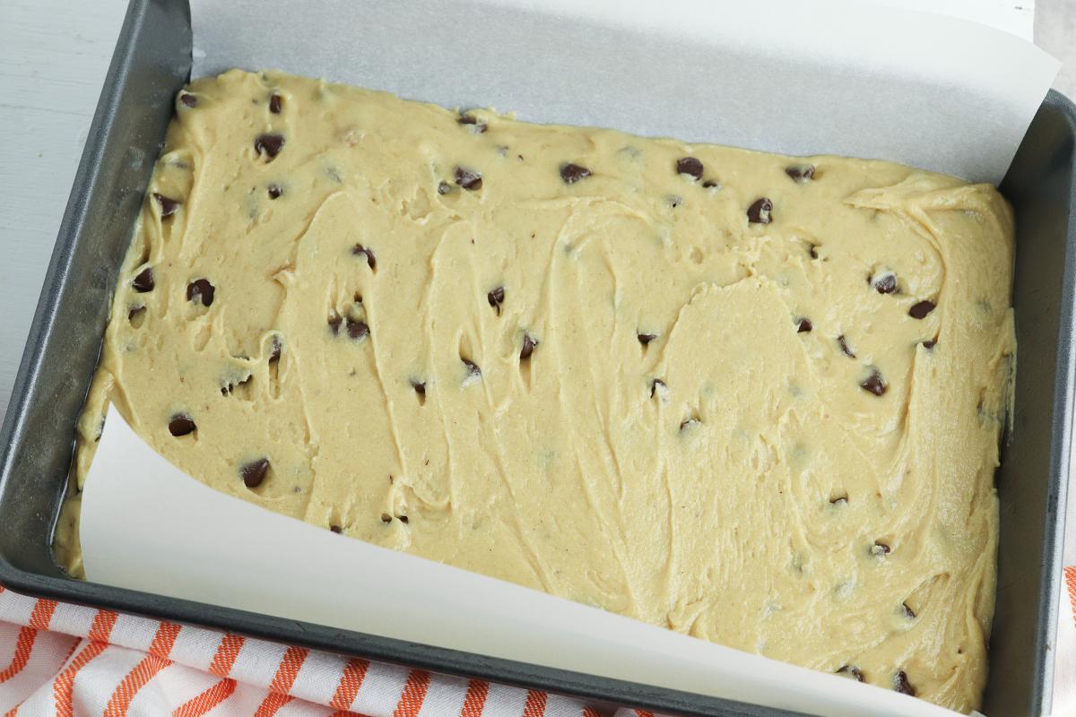 blondie batter in a prepared baking pan lined with parchment paper ready to go into the oven.