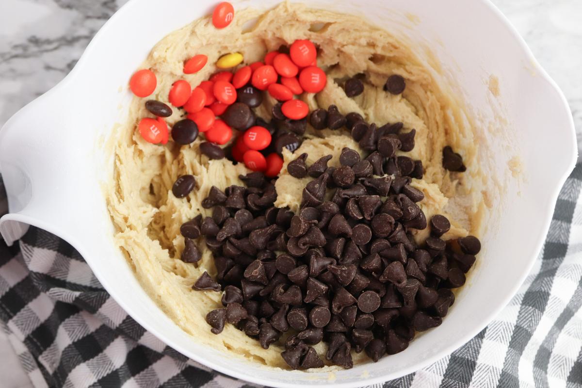 Chocolate chips and Halloween M&Ms added to the cookie dough for making Halloween Cookies.